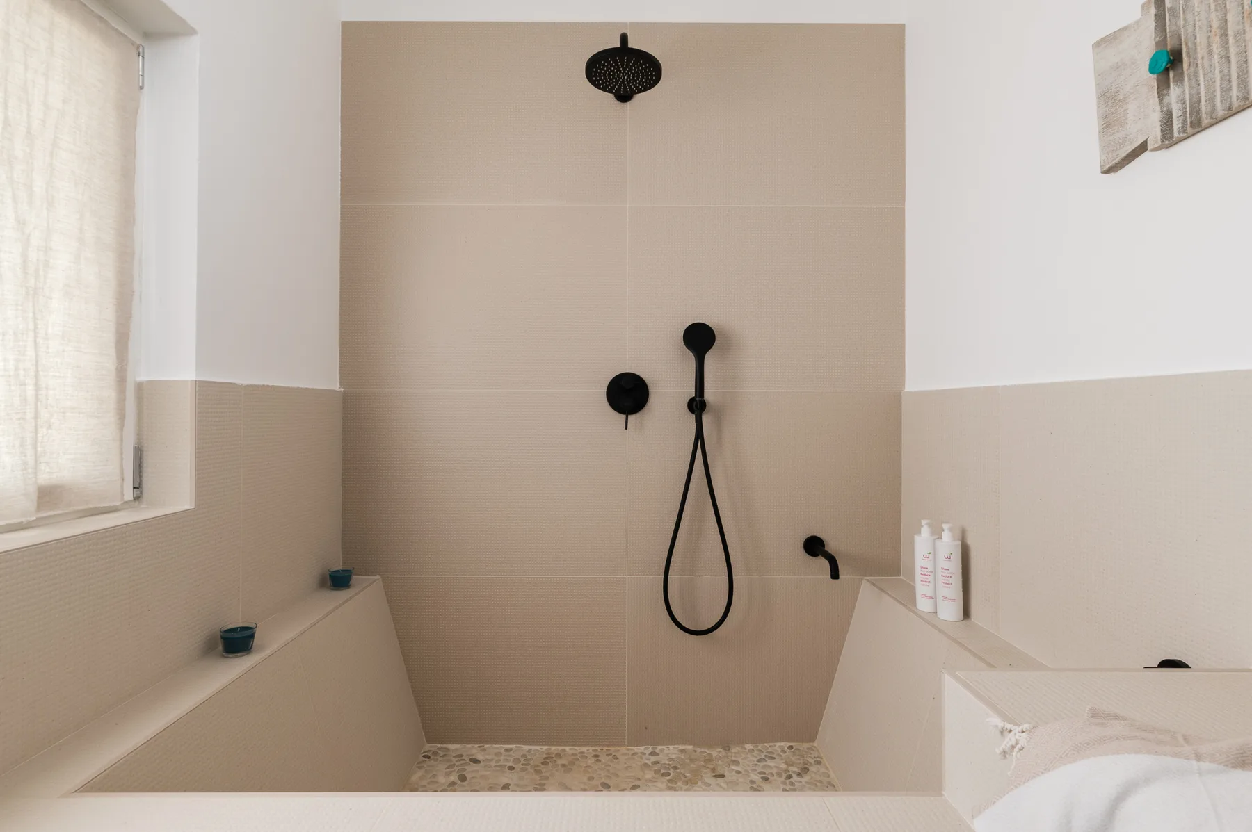 Una zona de ducha con rociador y controles montados en la pared.