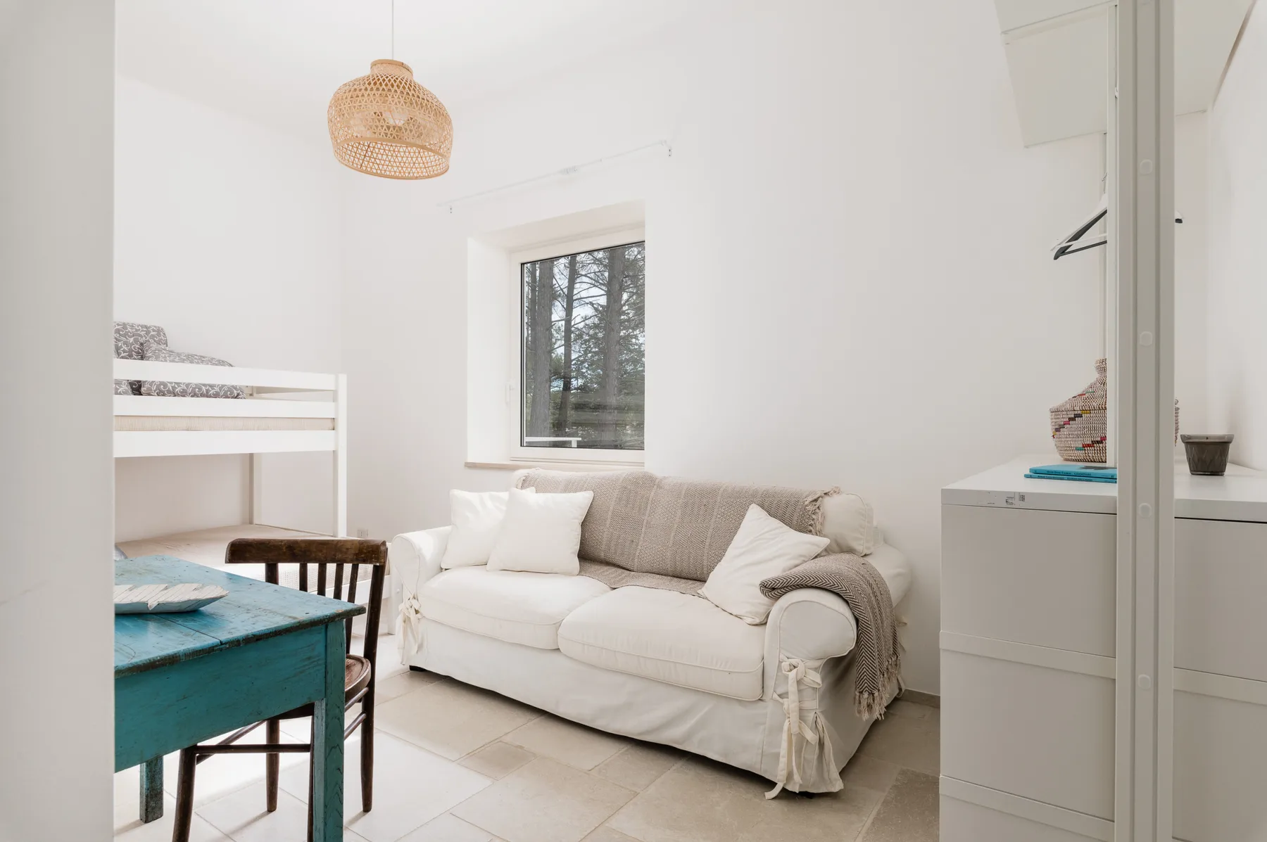 Una sala luminosa con un sofá blanco junto a una ventana.