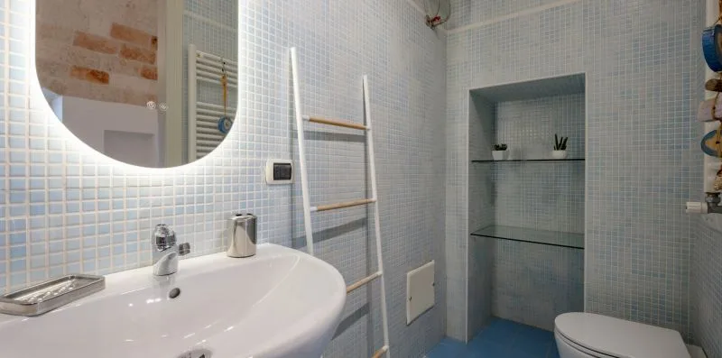 Un baño alicatado con lavabo, zona de ducha e inodoro.