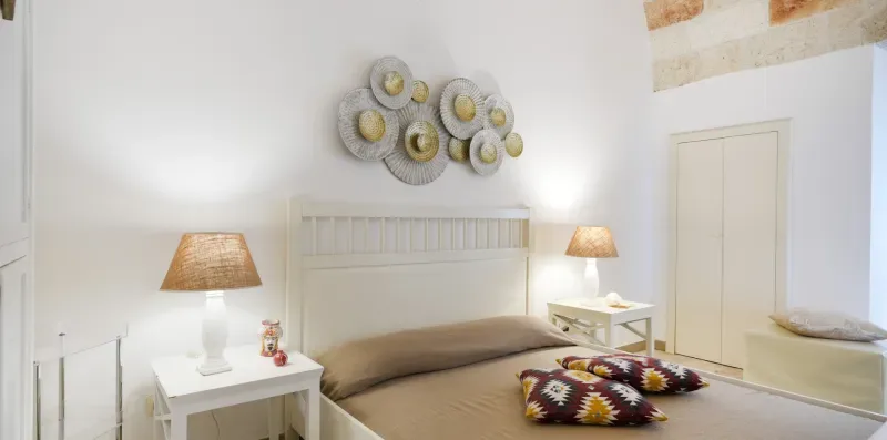 Un dormitorio con una cama, mesas auxiliares y una decoración en la pared.