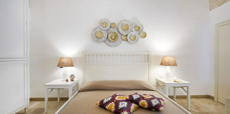 Un dormitorio con una cama, mesitas de noche a juego y decoración en la pared.