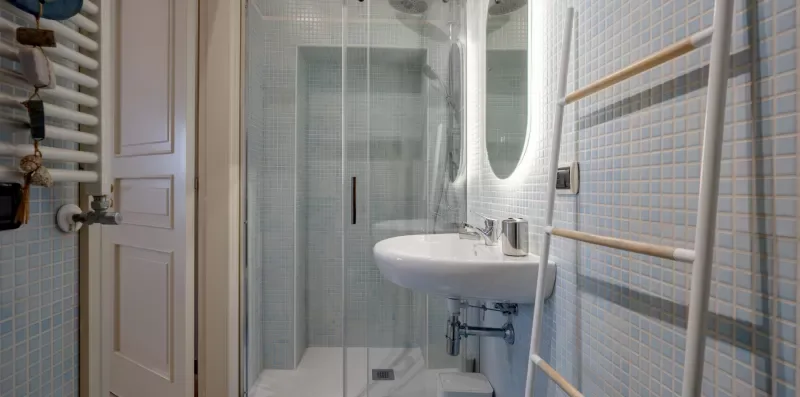 Un baño alicatado con lavabo y ducha de cristal.