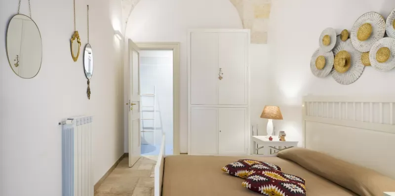 Un dormitorio luminoso con una cama, una mesita y un radiador de pared.
