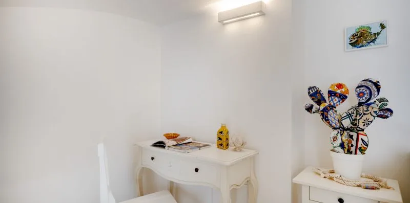 Un rincón luminoso con un escritorio blanco y cerámicas decorativas coloridas.