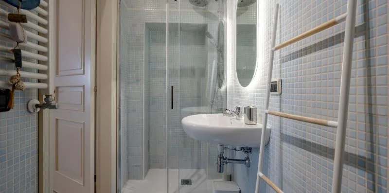 Un baño alicatado con ducha de vidrio y lavabo de pared.