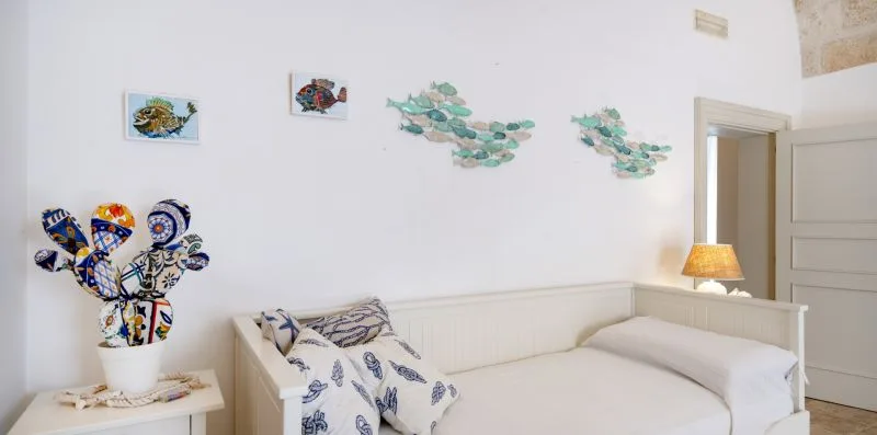 Un dormitorio luminoso con una cama y coloridas obras decorativas en la pared.