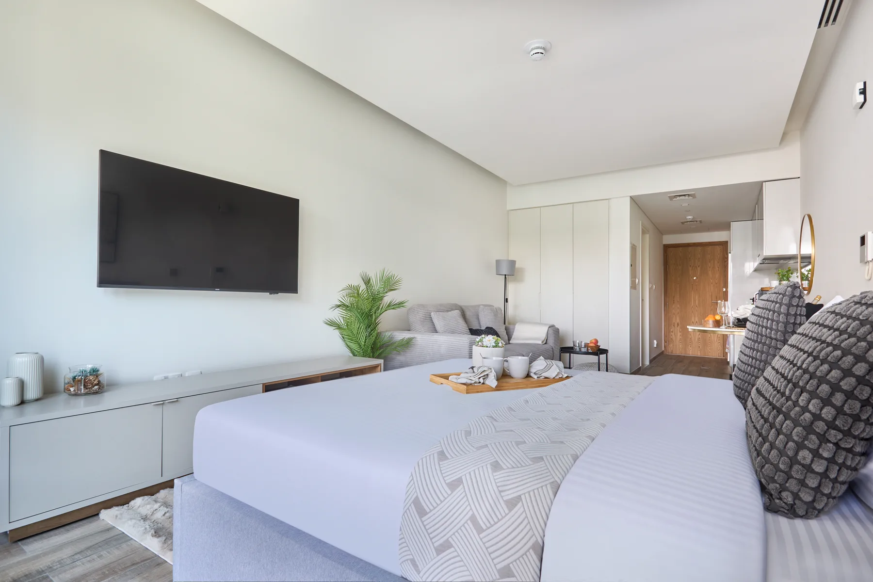 Dormitorio con cama, televisor montado en la pared y zona de estar.
