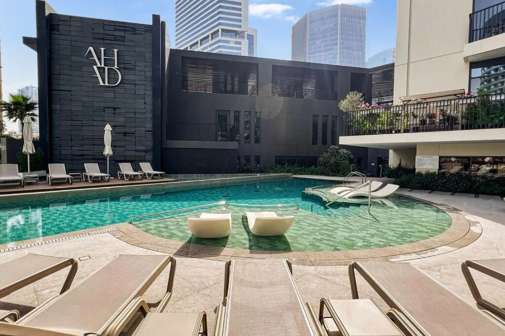 Una piscina al aire libre está rodeada de asientos y edificios urbanos modernos.