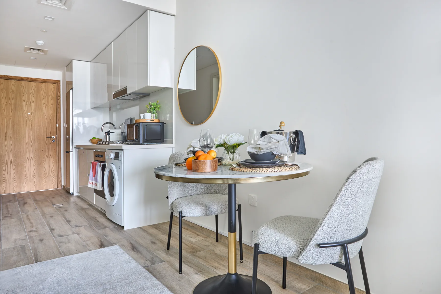 Comedor con una mesa redonda y sillas junto a una cocina compacta.