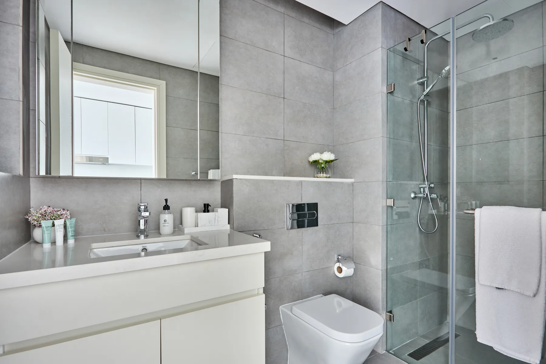 Un baño moderno con lavabo, inodoro y ducha de vidrio.