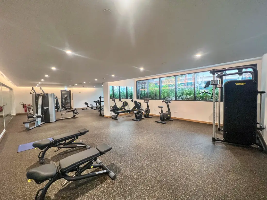 Una sala de fitness con máquinas de ejercicio y bancos de pesas.