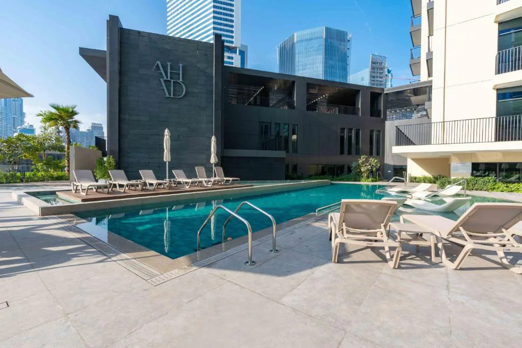 Una piscina al aire libre está rodeada de asientos y edificios modernos.