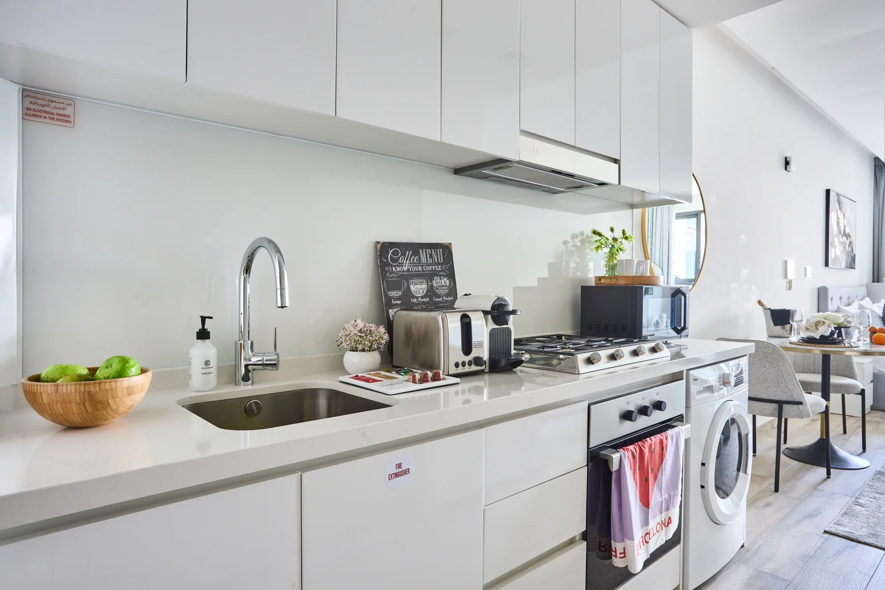 Una cocina luminosa con gabinetes blancos, un fregadero y una encimera.