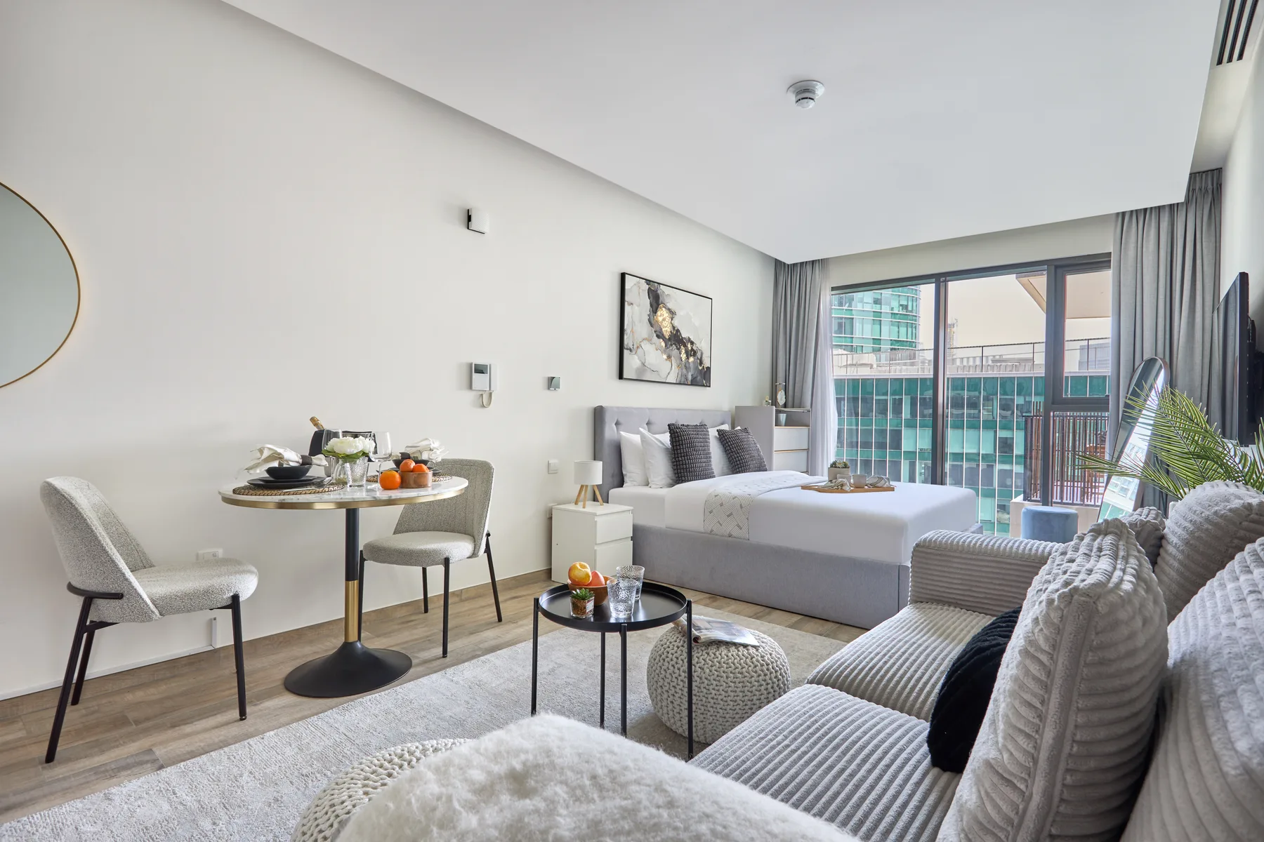Sala de estar con cama, zona de estar y grandes ventanales.