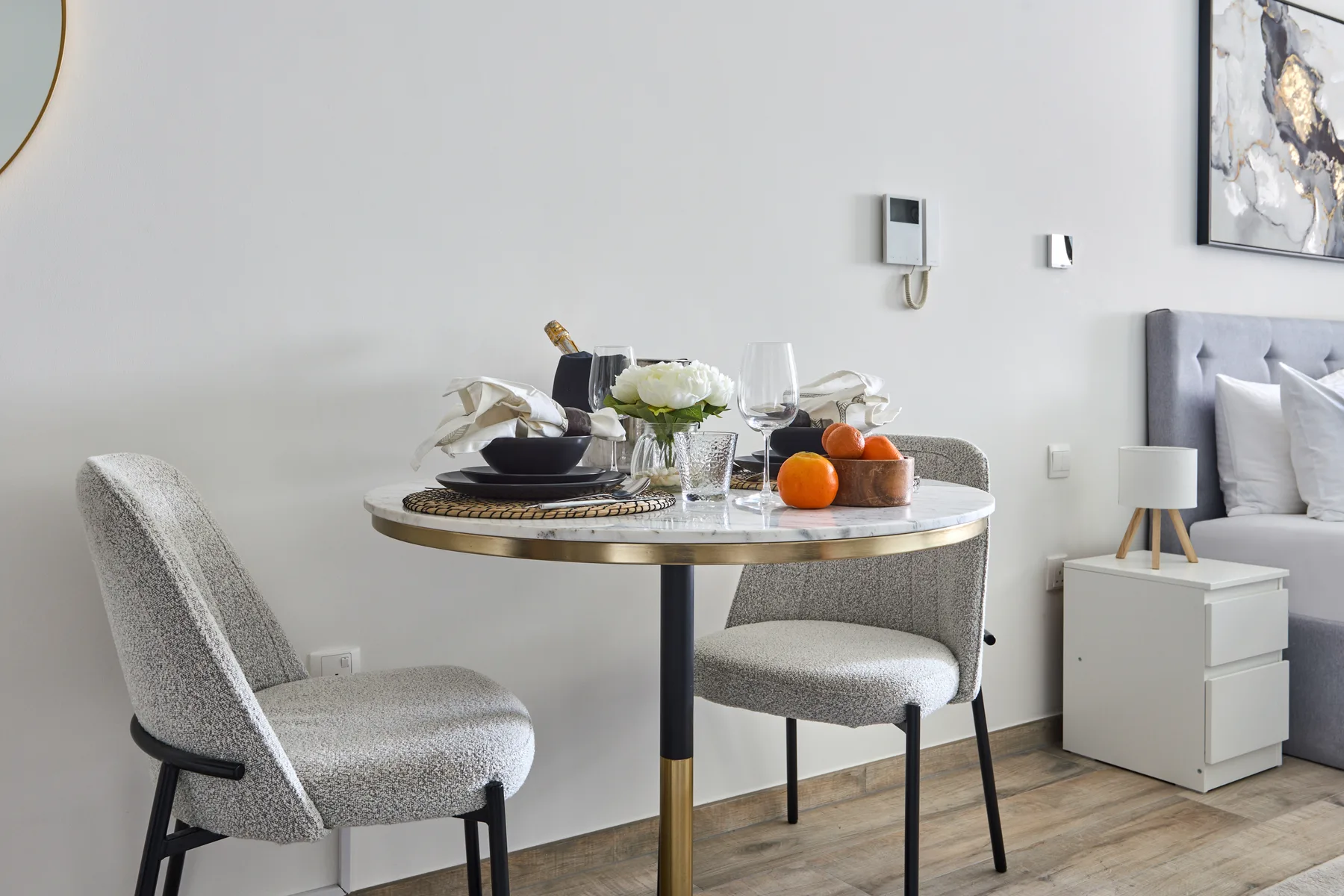 Una zona de estar en un dormitorio con una mesa redonda preparada con platos y fruta.