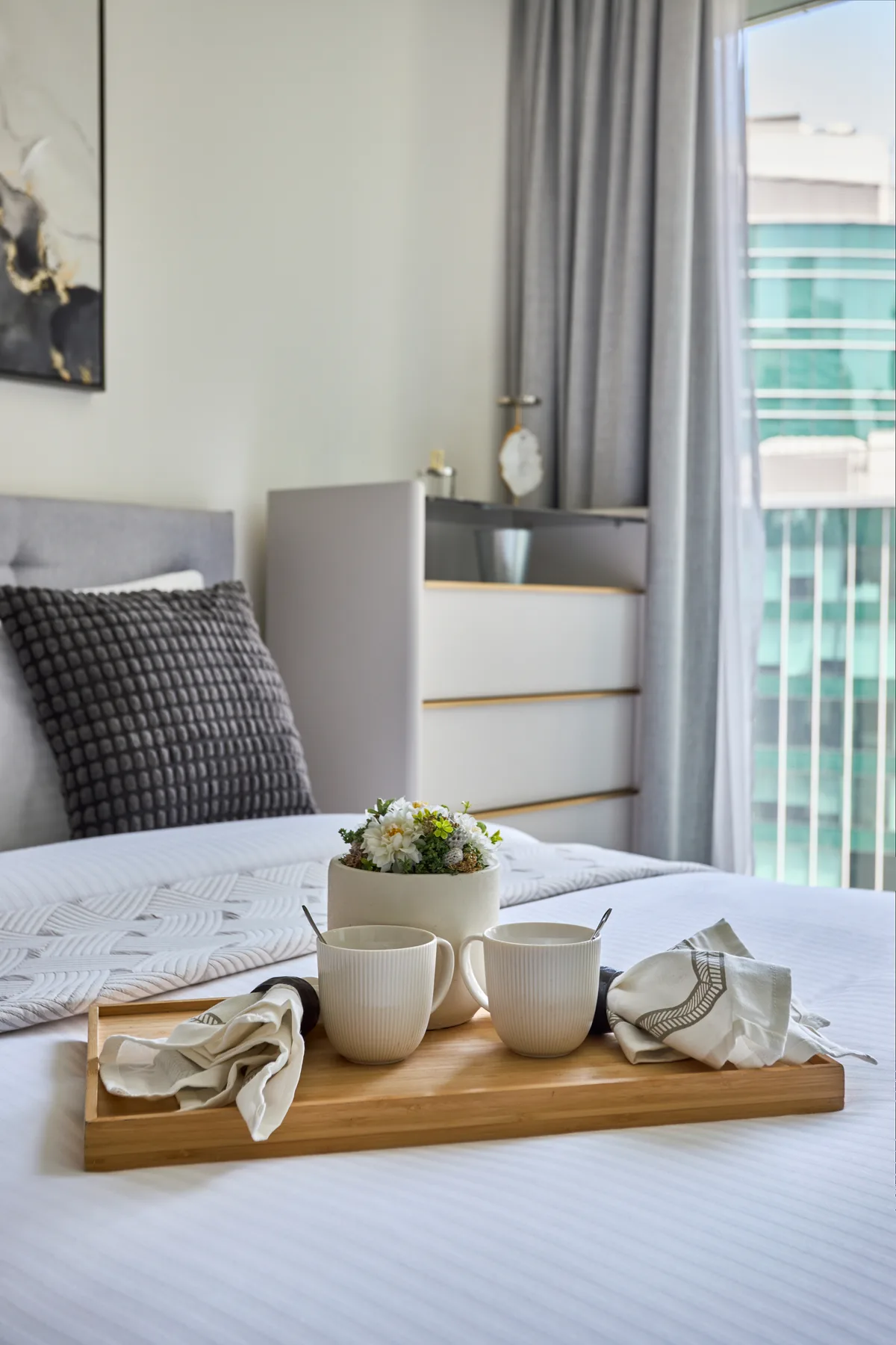 Un dormitorio con una cama bien hecha y una bandeja de desayuno junto a la ventana.