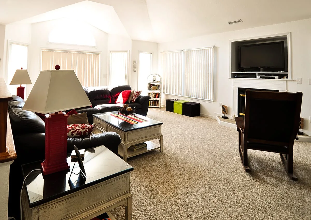 A bright living room with seating, a coffee table, and a television.