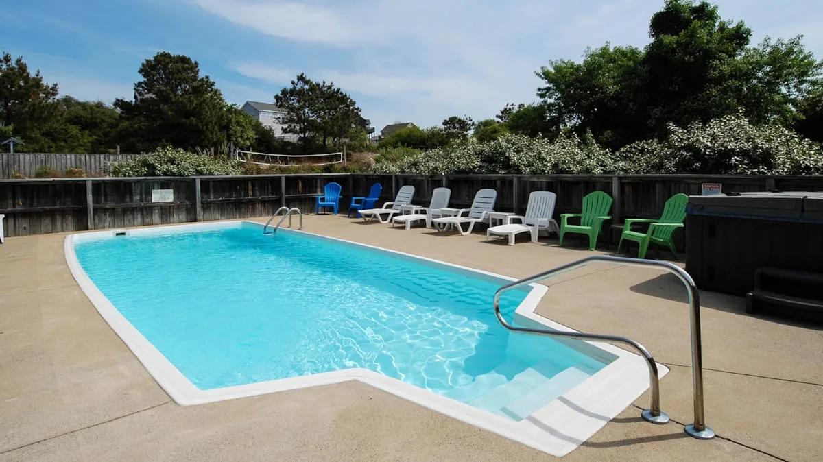 An outdoor swimming pool with seating arranged along the surrounding deck.