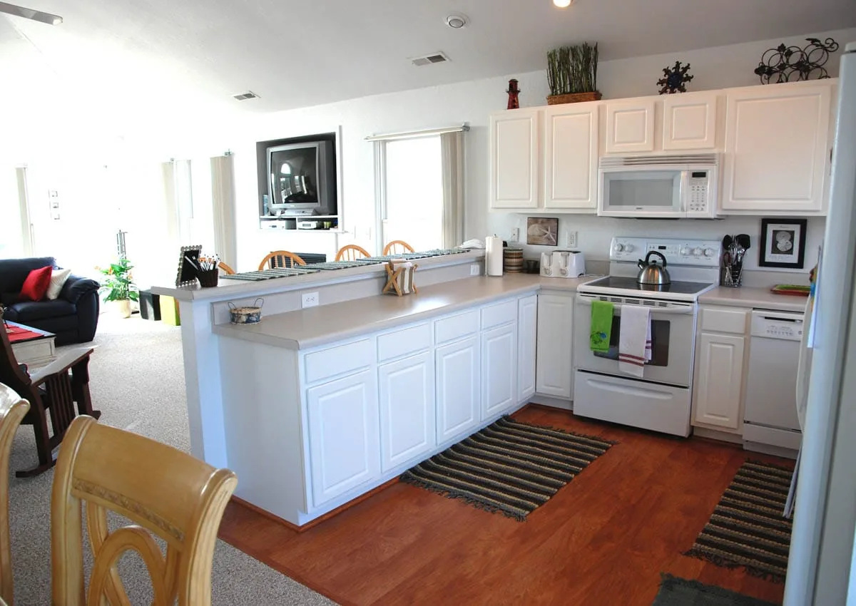 A bright kitchen with white cabinets, a long island, and a range.