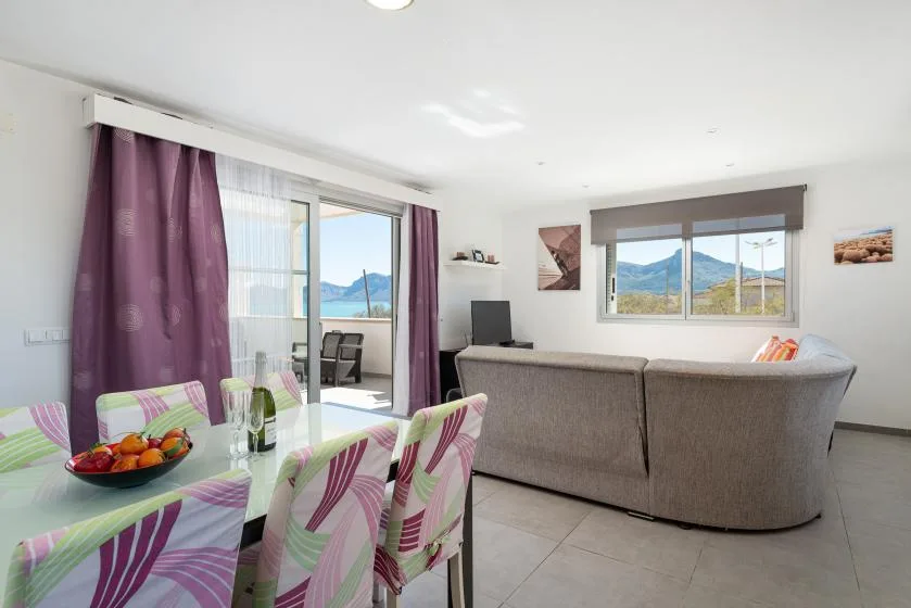 A bright living and dining area with a table, seating, and mountain views through the windows.