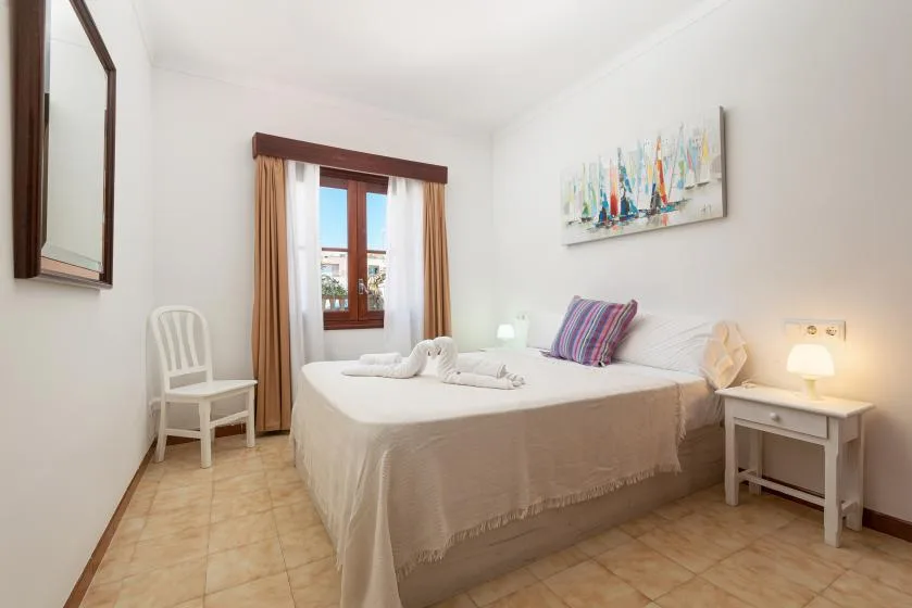 A bedroom with a bed, a window, and a white chair.