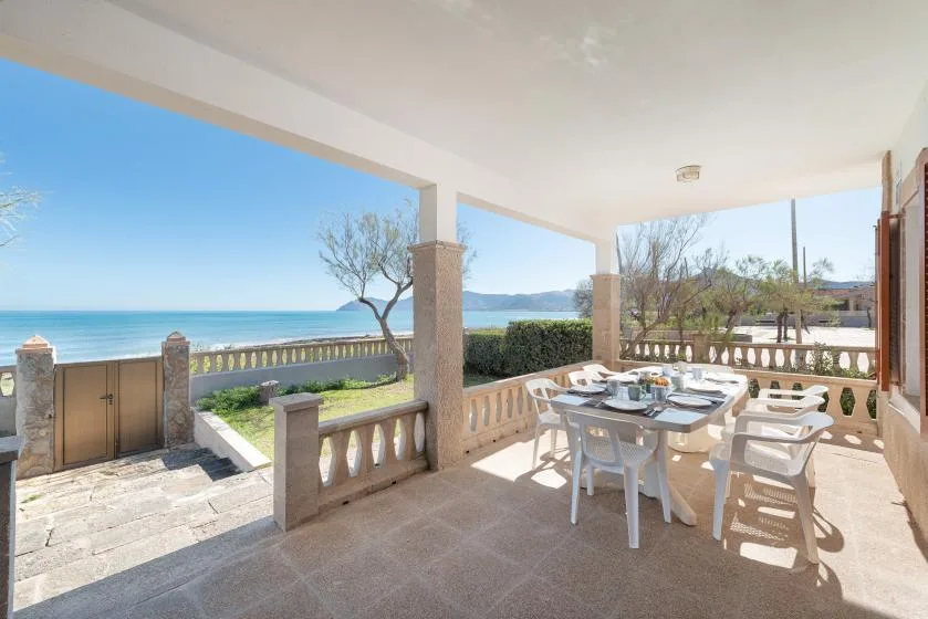 Una terraza cubierta junto al mar, con una mesa de comedor al aire libre y vistas al agua.