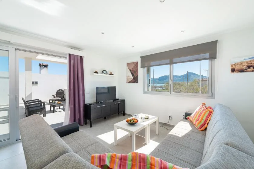 A bright living room with gray seating, a coffee table, and large windows.