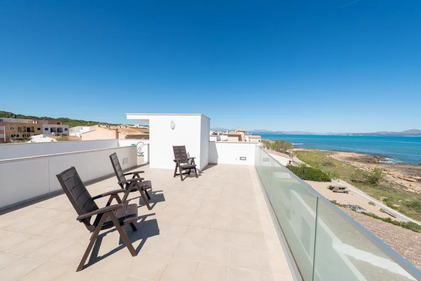 A rooftop terrace with lounge seating overlooks the sea.
