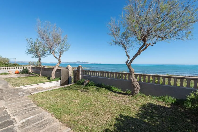 Un paseo junto al mar bordea una zona de césped y una barandilla baja.