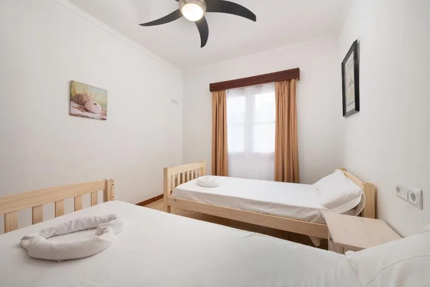 A bedroom with two single beds, a window, and warm-colored curtains.