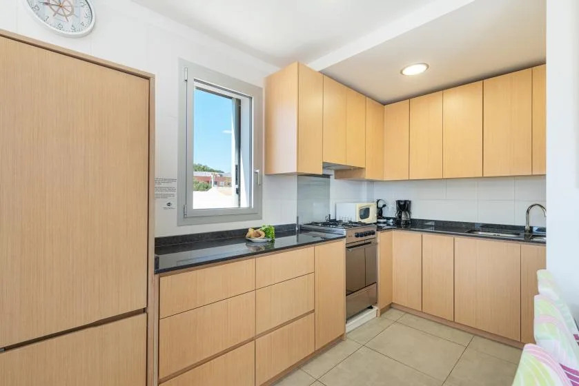A bright kitchen with light wood cabinets and a window above the counter.