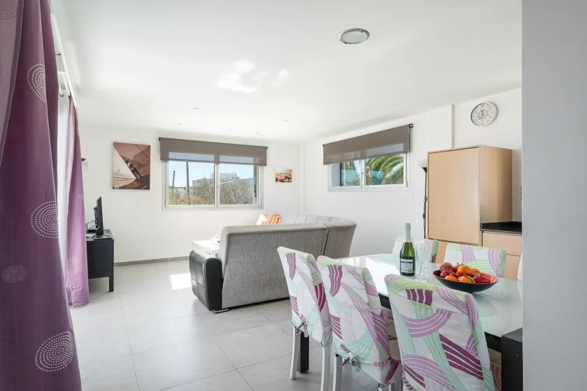 A bright living and dining area with a gray sofa and a dining table.