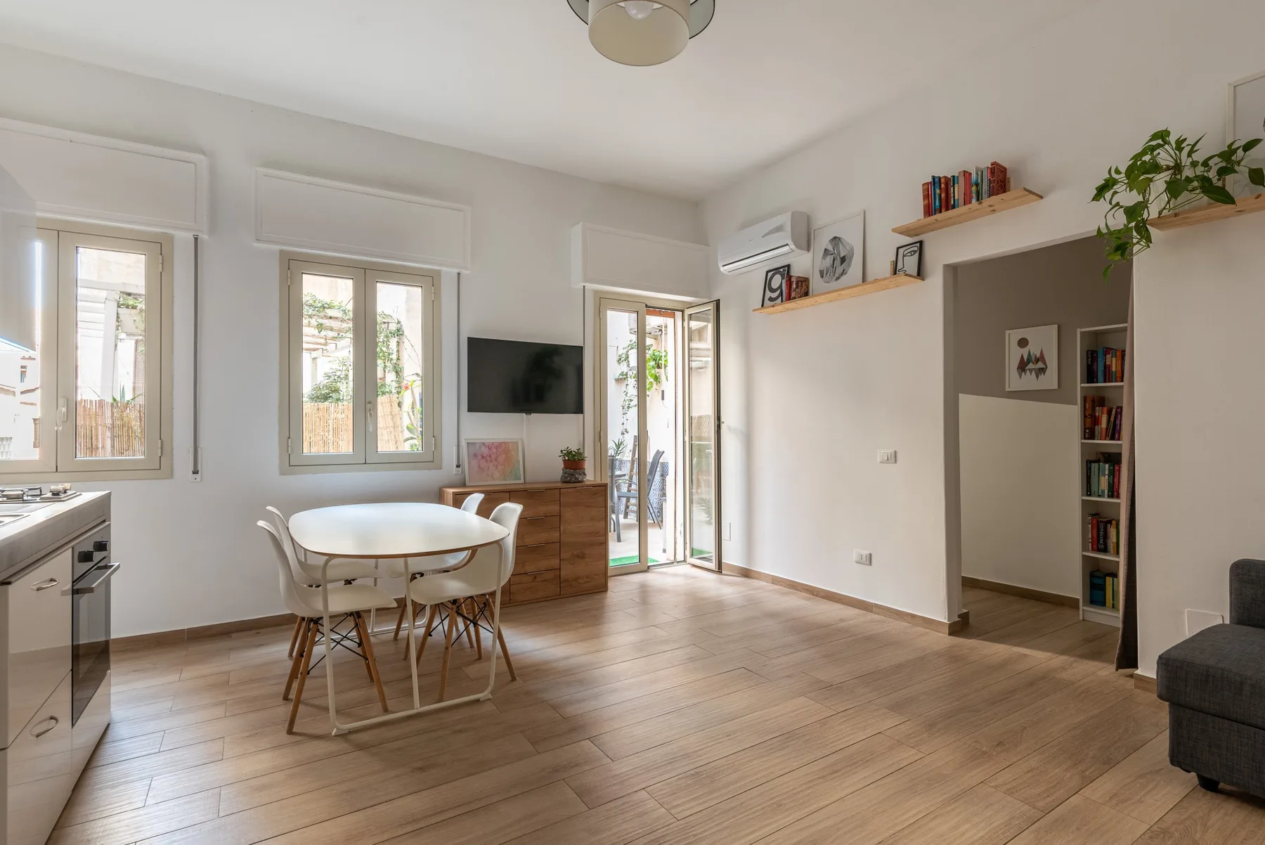 A bright open-plan dining and living area with a table beside the windows.