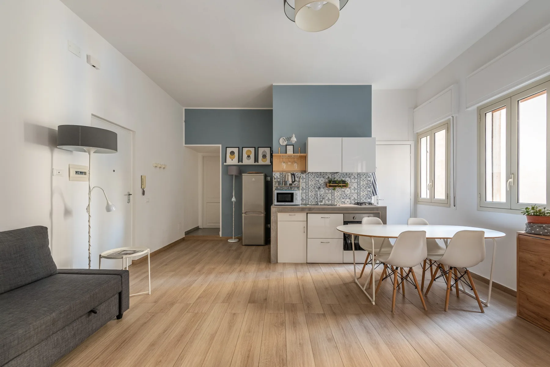 A bright open-plan living and dining area with a kitchen and large windows.