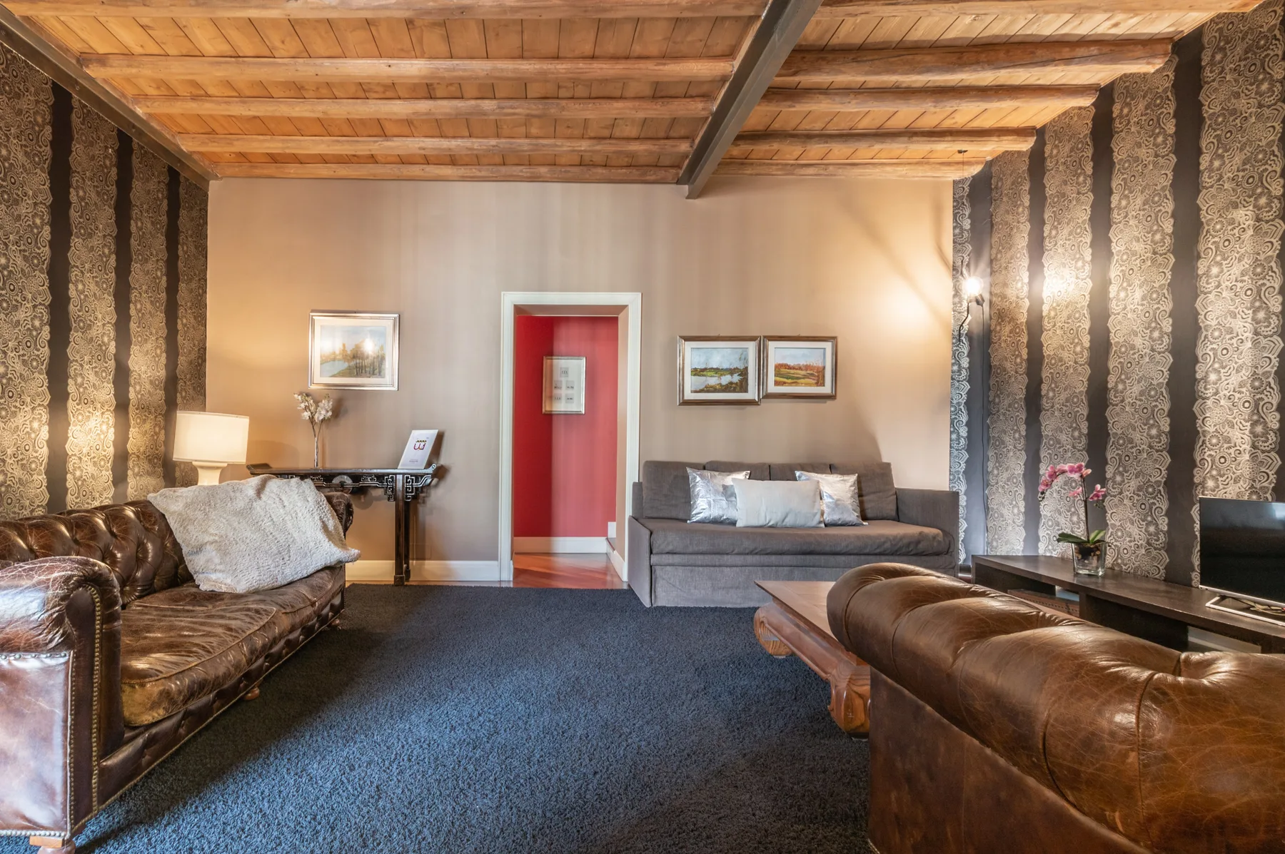 Una sala de estar con asientos de cuero, un sofá gris y una puerta roja.