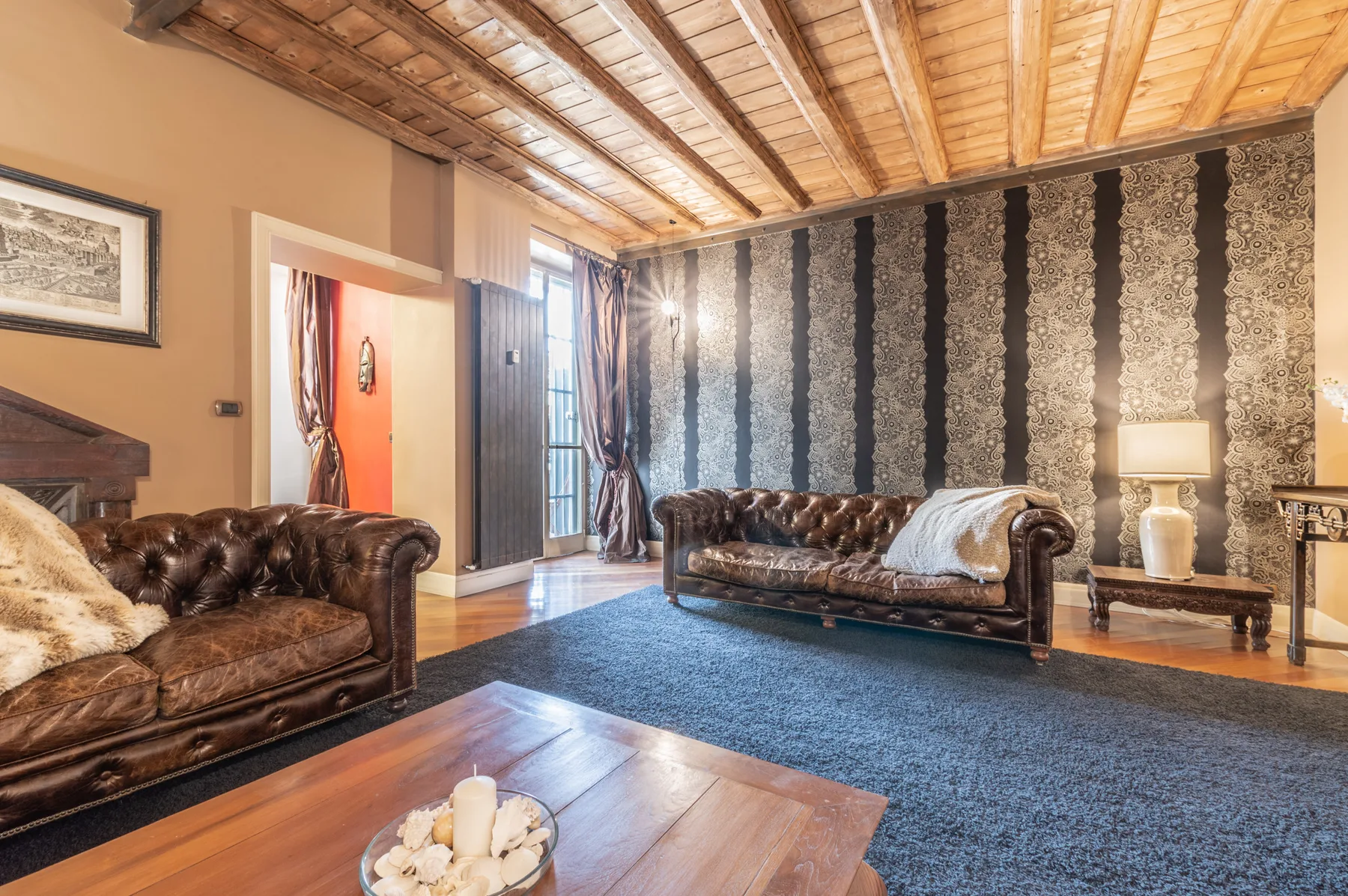 Una sala de estar con asientos de cuero, una pared estampada y un techo de madera visto.