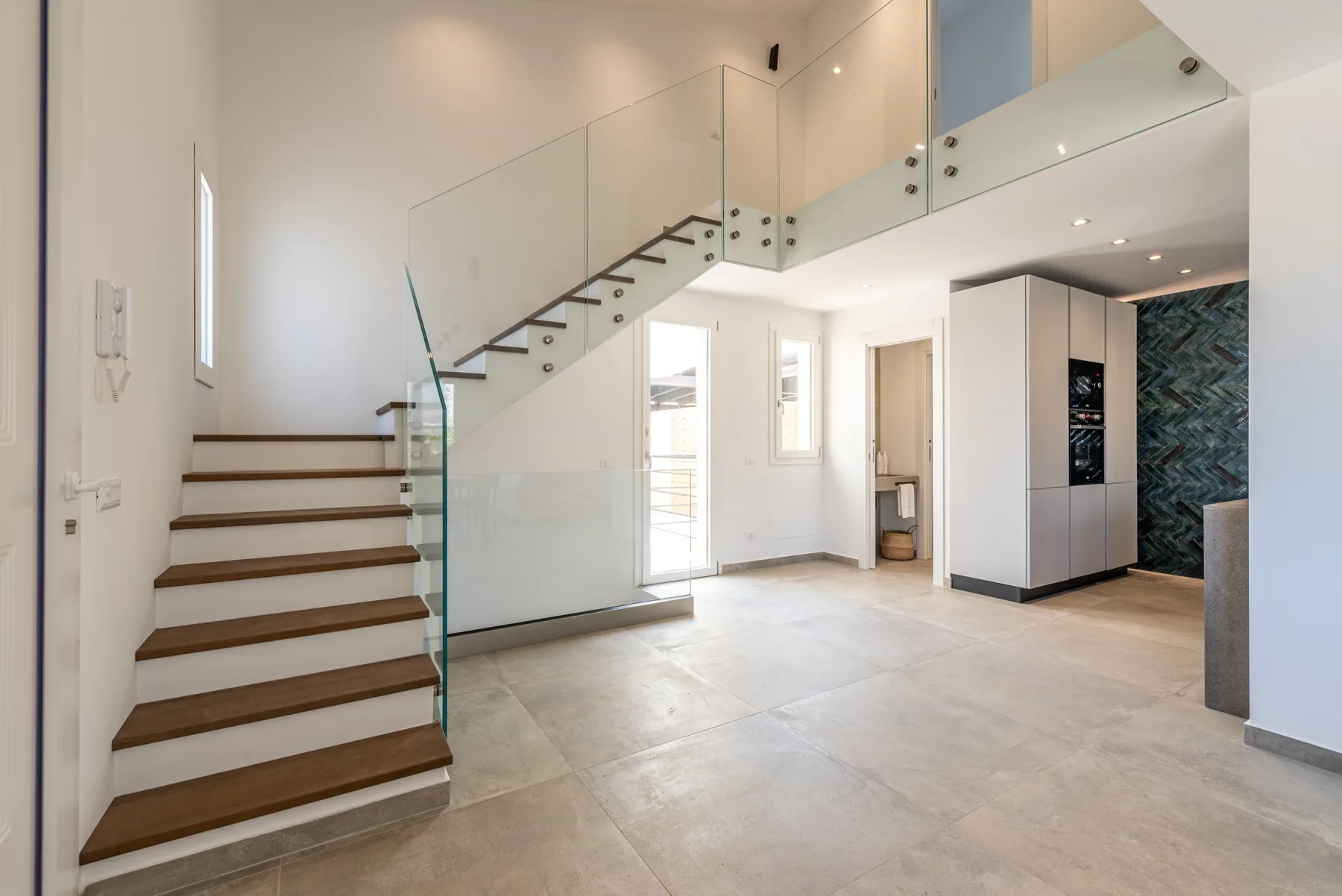 Un interior moderno y luminoso con una escalera y una cocina abierta.