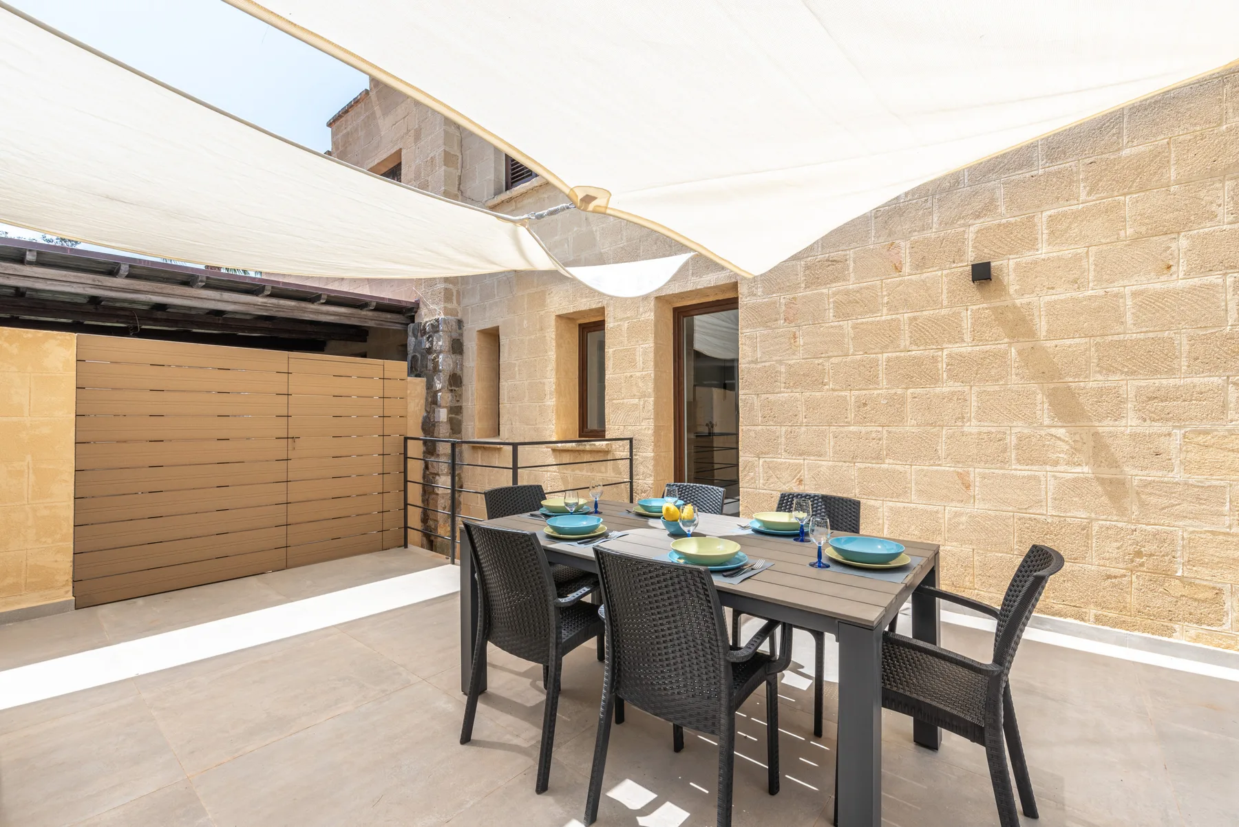 Un comedor al aire libre con mesa y sillas bajo una cubierta blanca de sombra.