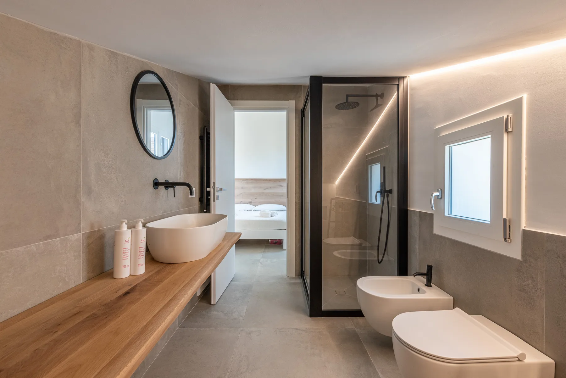 Un baño moderno con tocador de madera, lavabo, ducha e inodoro.
