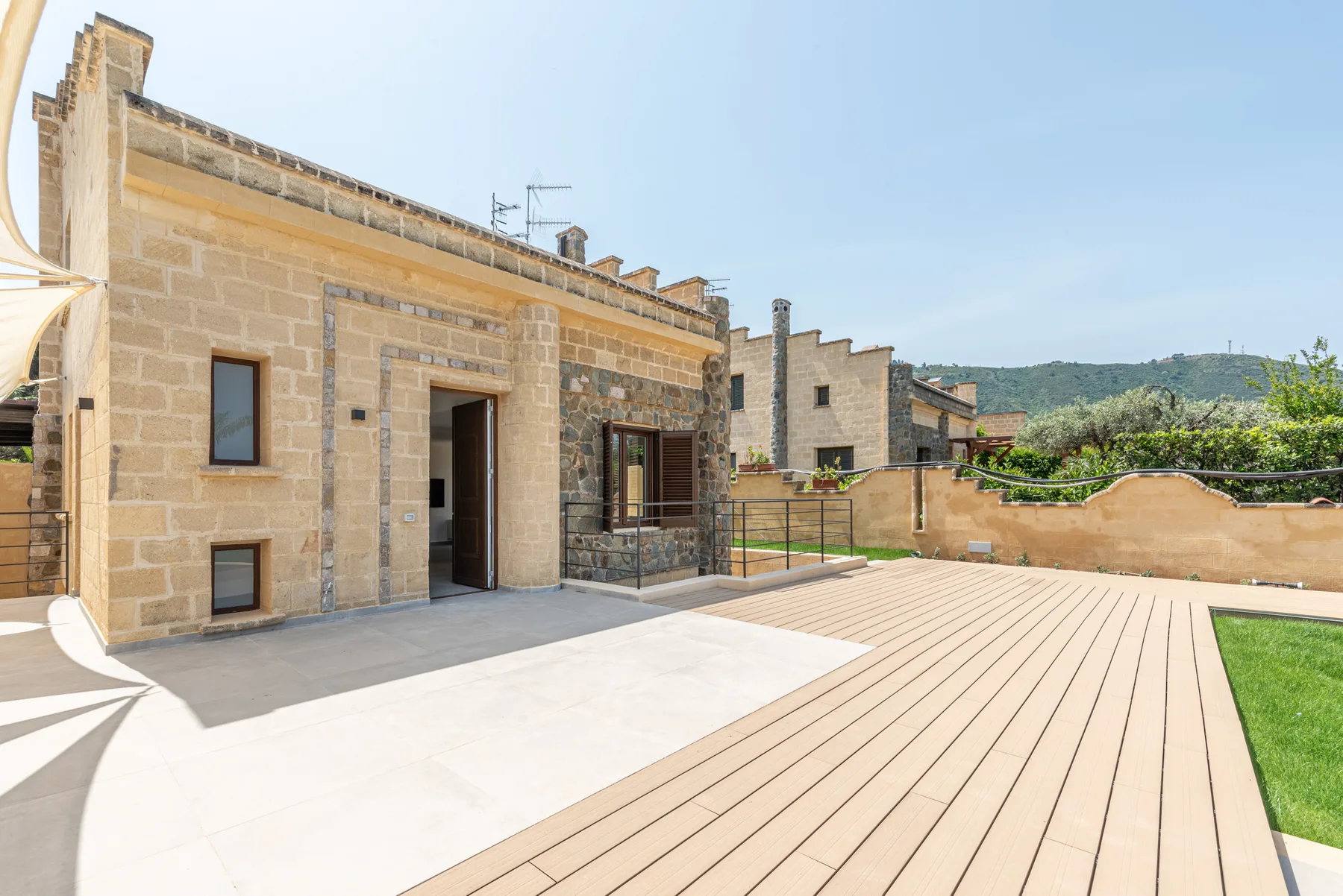 Un edificio de piedra da a un amplio patio pavimentado con una tarima de madera.