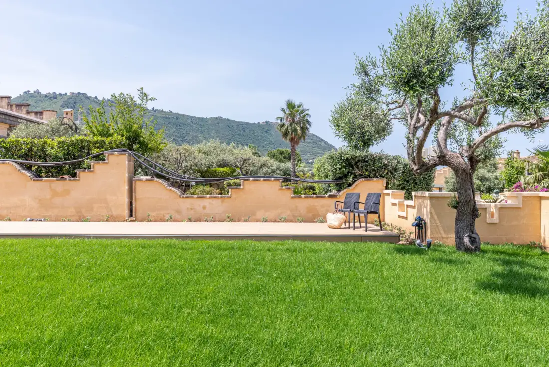 Un jardín ajardinado con un amplio césped, árboles y asientos al aire libre.