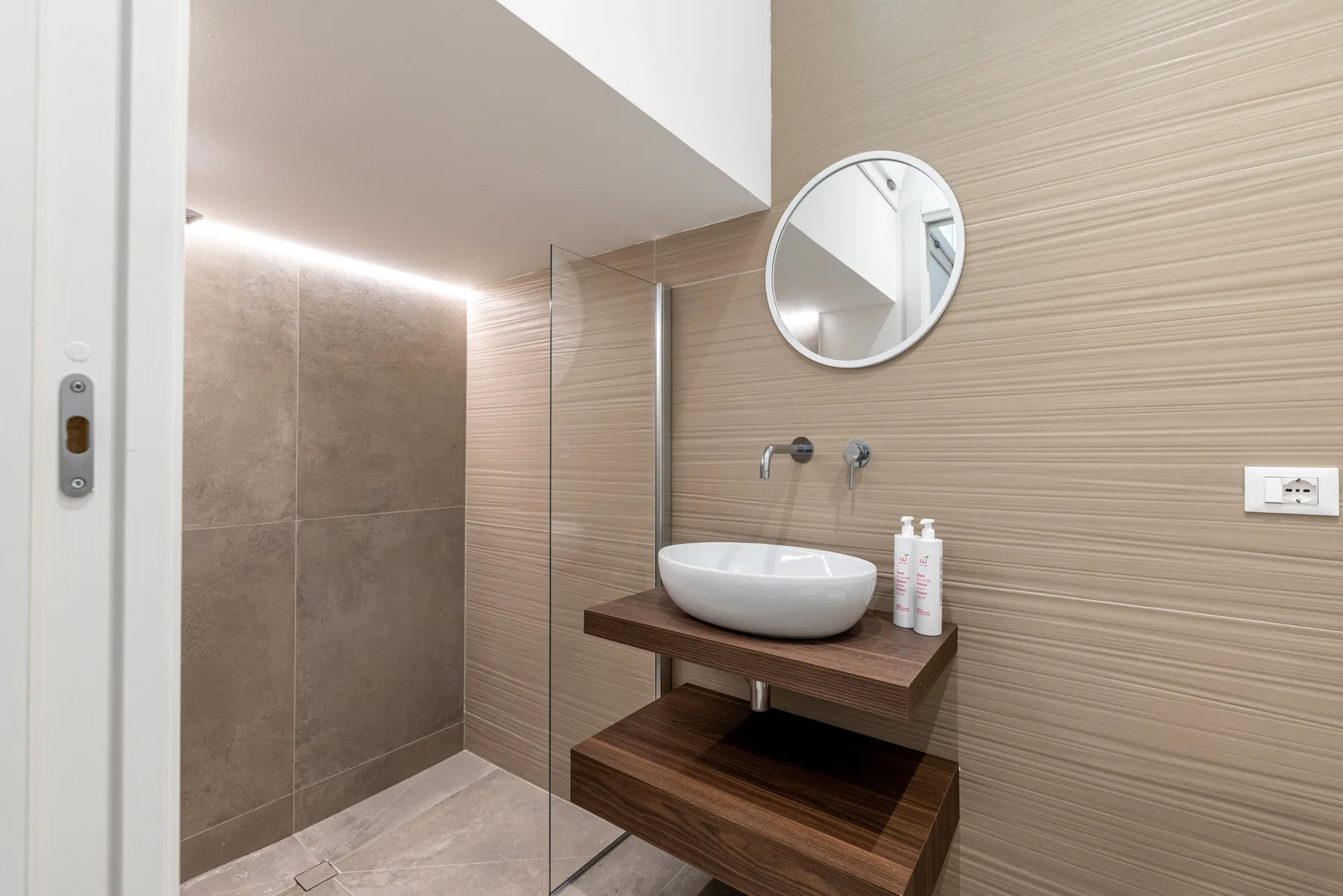 Un baño moderno con un espejo redondo sobre un lavabo de recipiente.