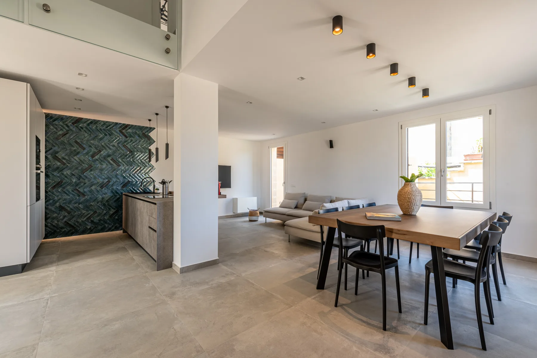 Una sala-comedor de concepto abierto con una mesa junto a ventanas grandes.