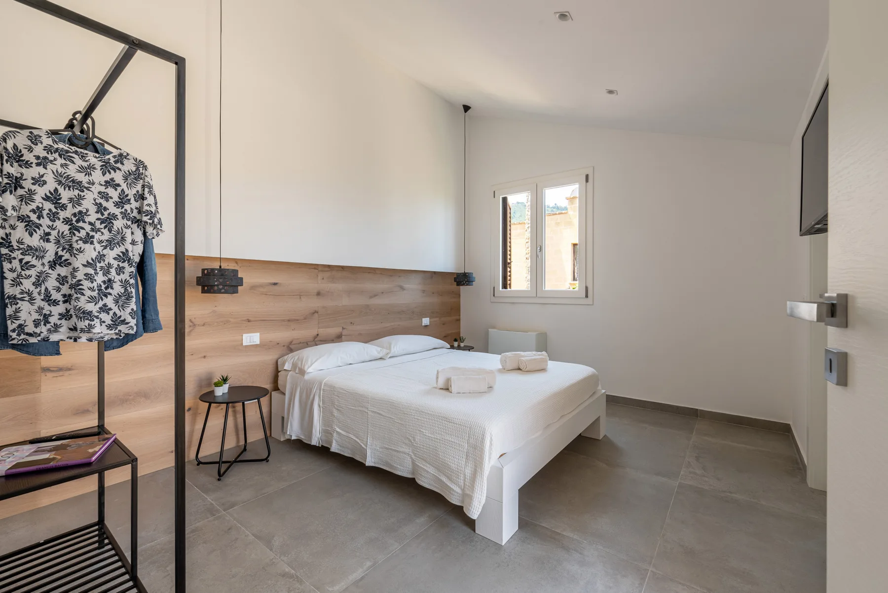 Un dormitorio con una cama, una mesa de noche y una ventana.