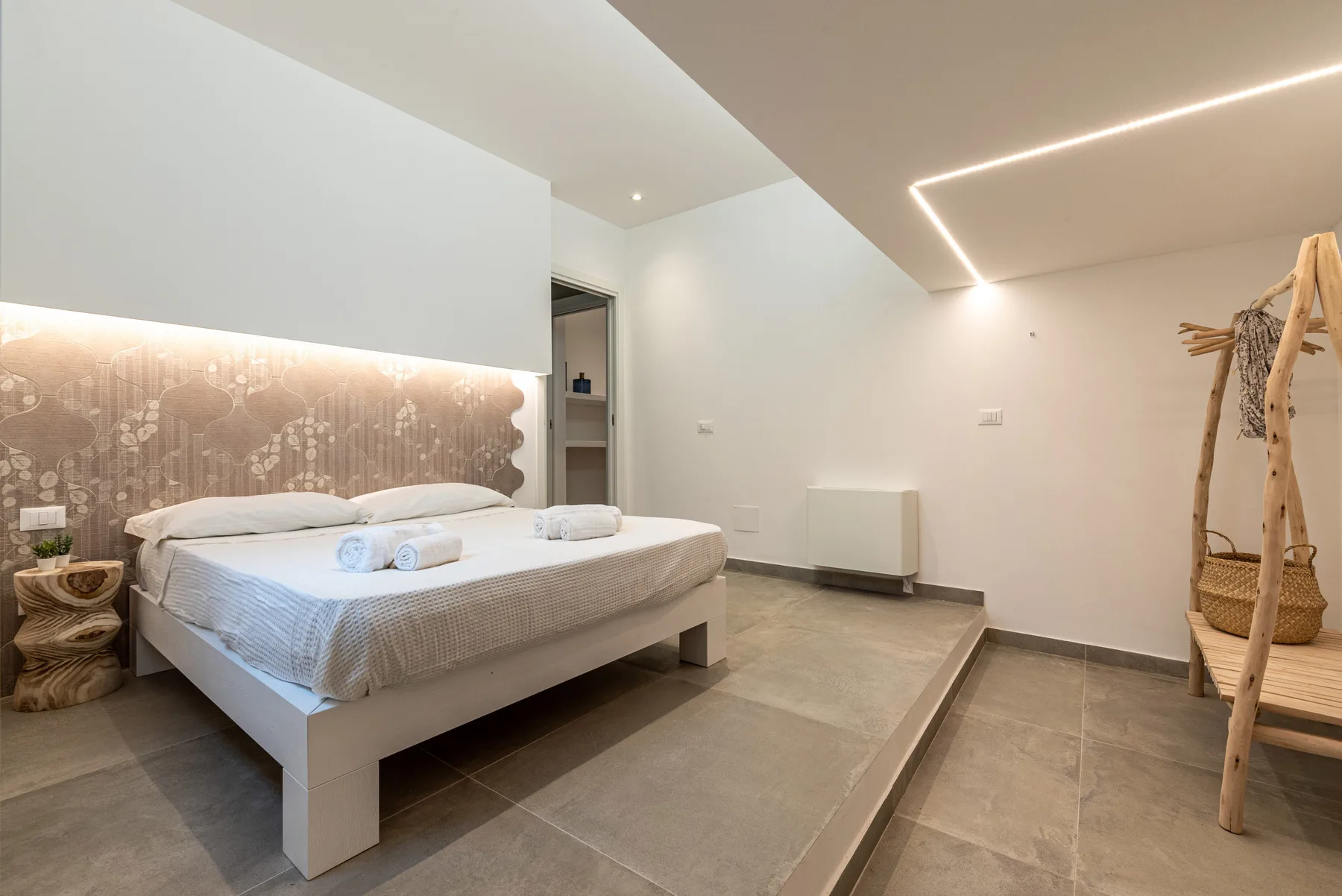 Un dormitorio moderno con una cama elevada e iluminación cálida.