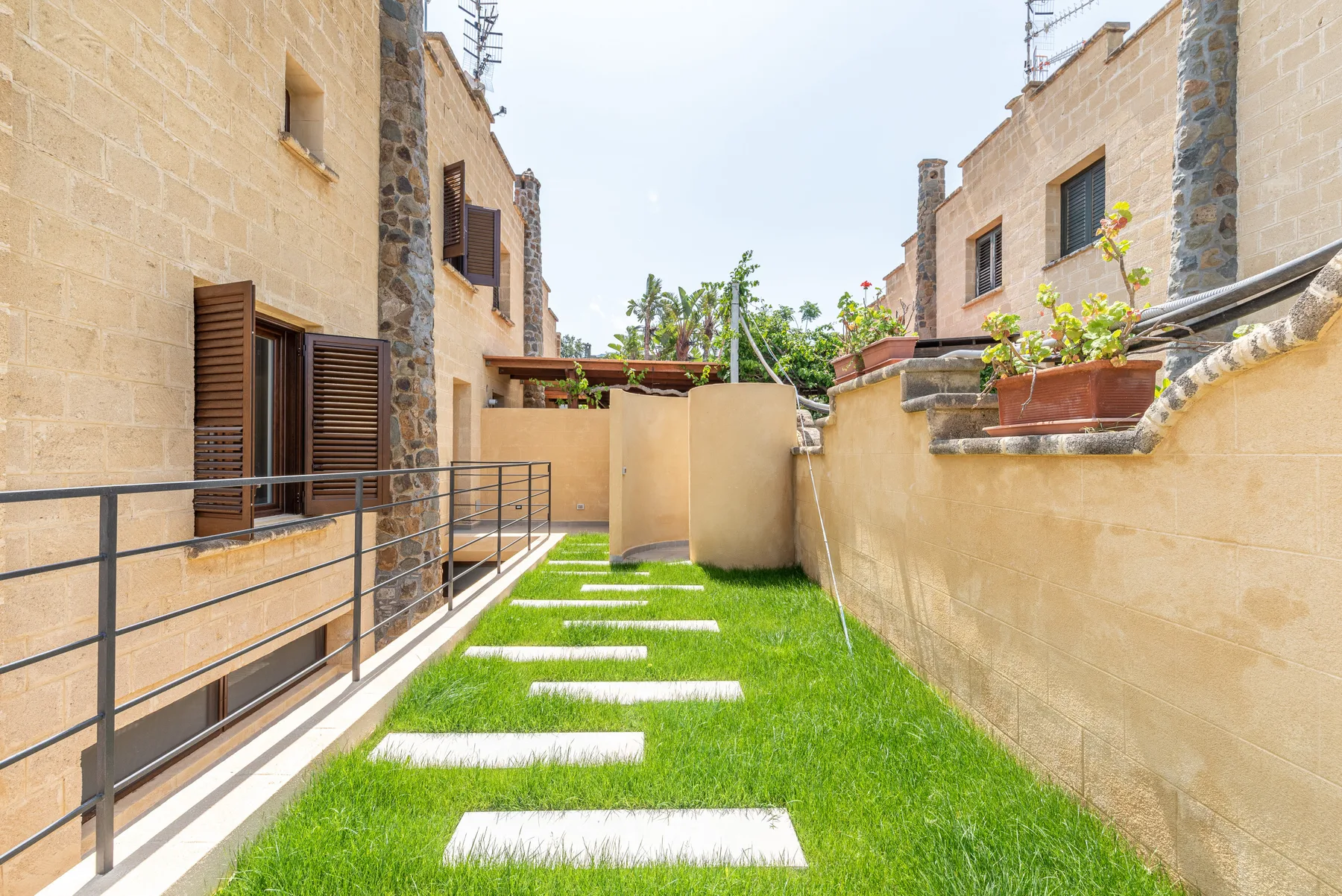 Un patio con césped entre edificios de piedra tiene un camino de losas.