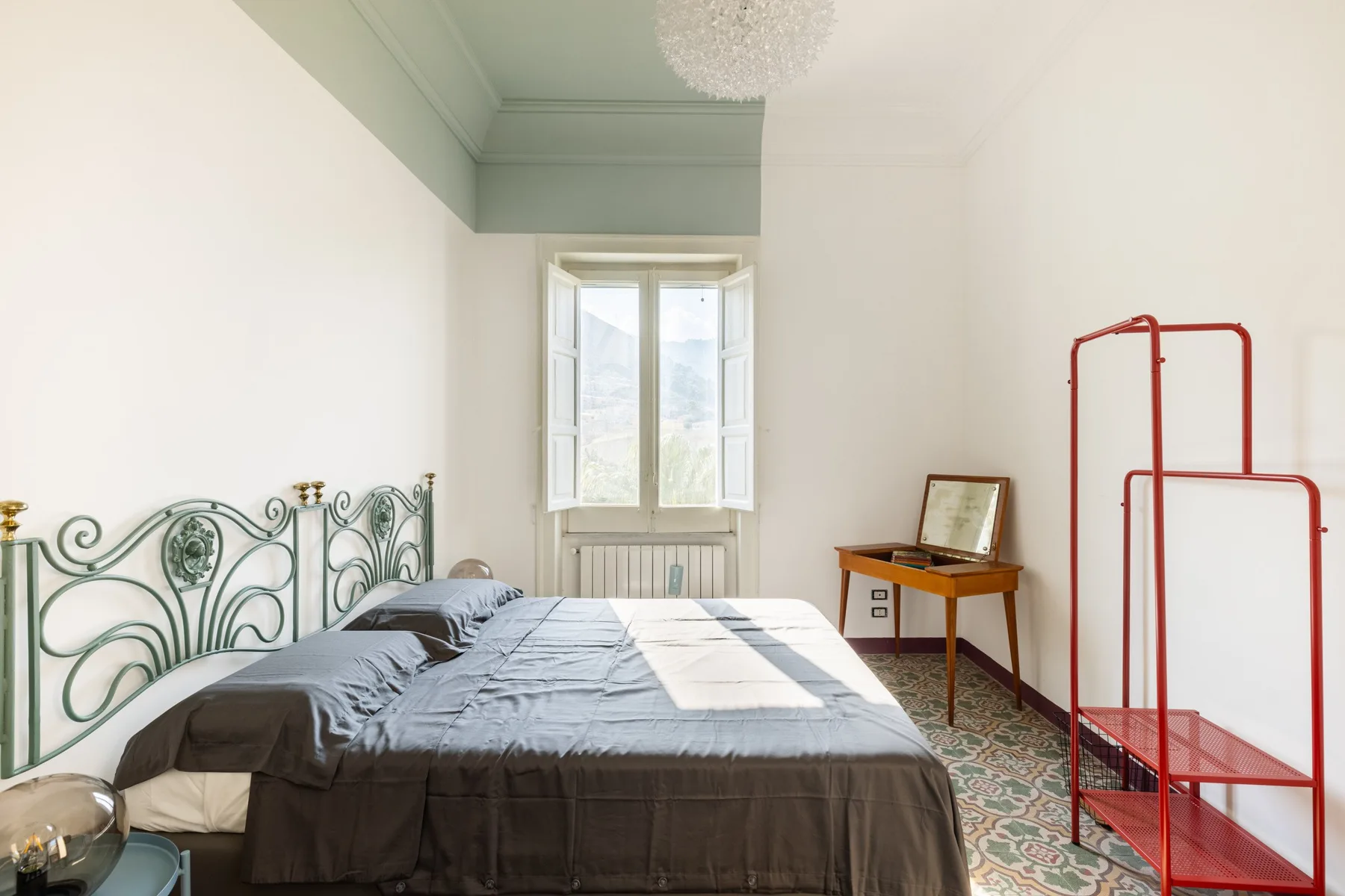 A bedroom with a bed beneath a window and a small desk.