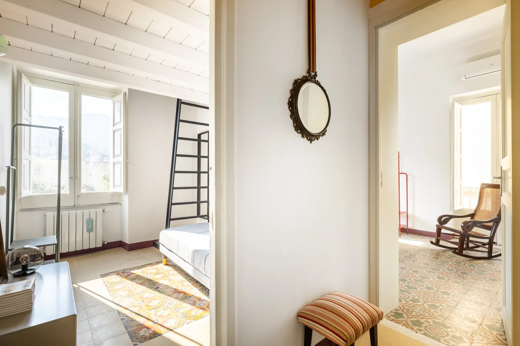 Un dormitorio luminoso con una cama junto a ventanas grandes y una escalera.