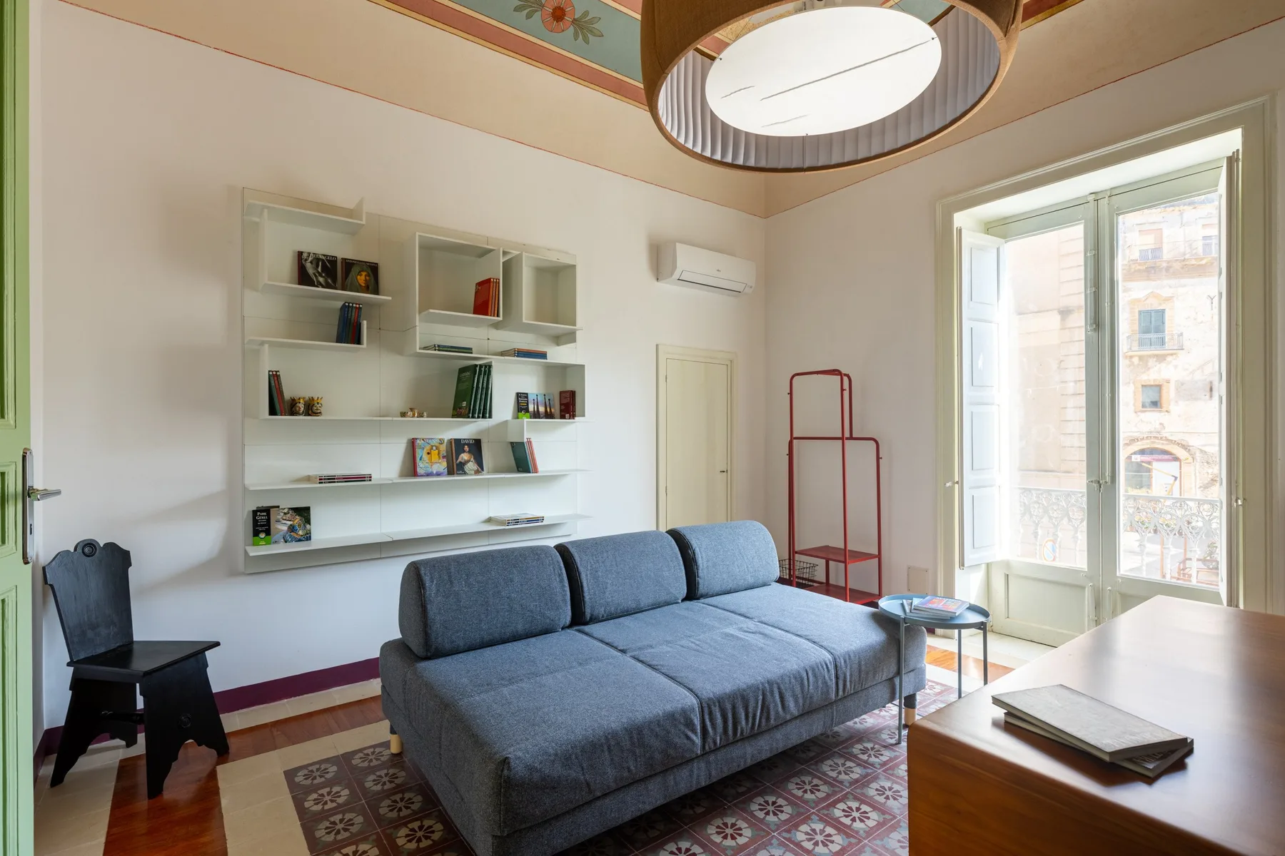 Una sala luminosa con un sofá gris junto a una ventana grande.