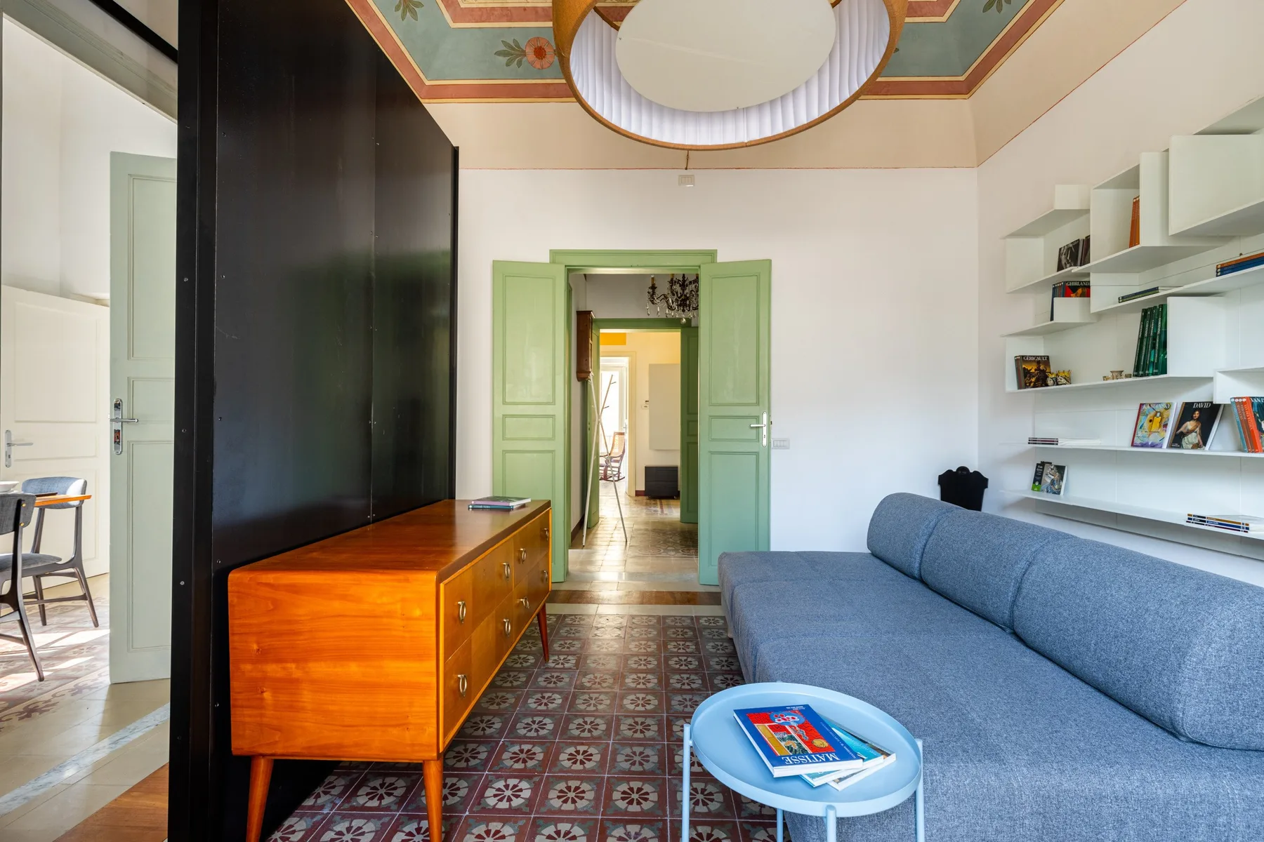 A living room with blue seating, built-in shelves, and patterned tile flooring.